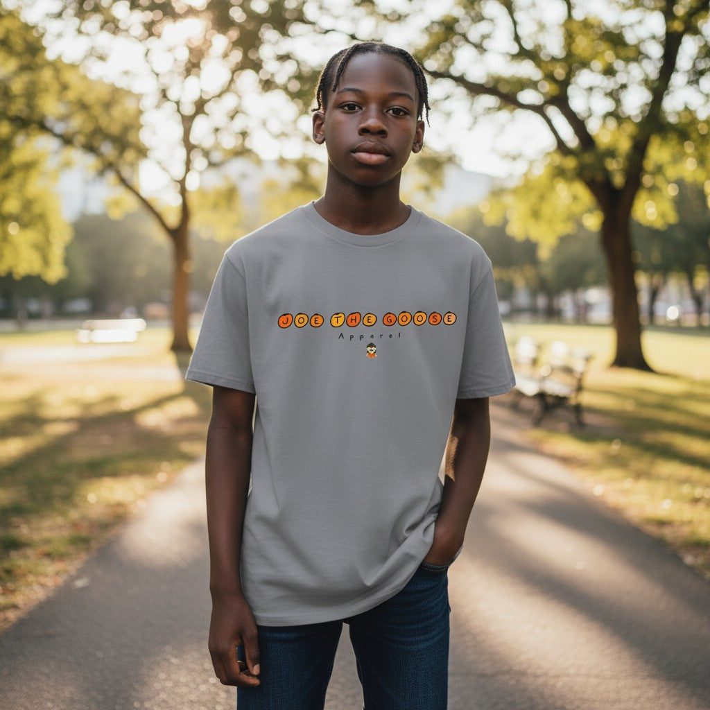 Young man wearing a grey Joe the Goose Apparel heavy cotton t-shirt with orange circle logo in a park setting.