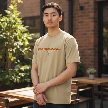 Man wearing a beige Joe the Goose Apparel heavy cotton classic tee with a circular logo graphic outdoors.