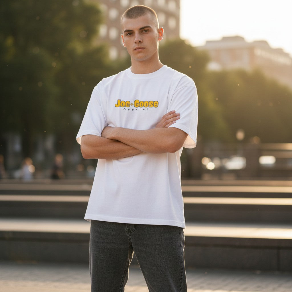 Model wearing a white Joe the Goose Apparel heavy cotton tee with relaxed fit and logo in an outdoor urban setting.