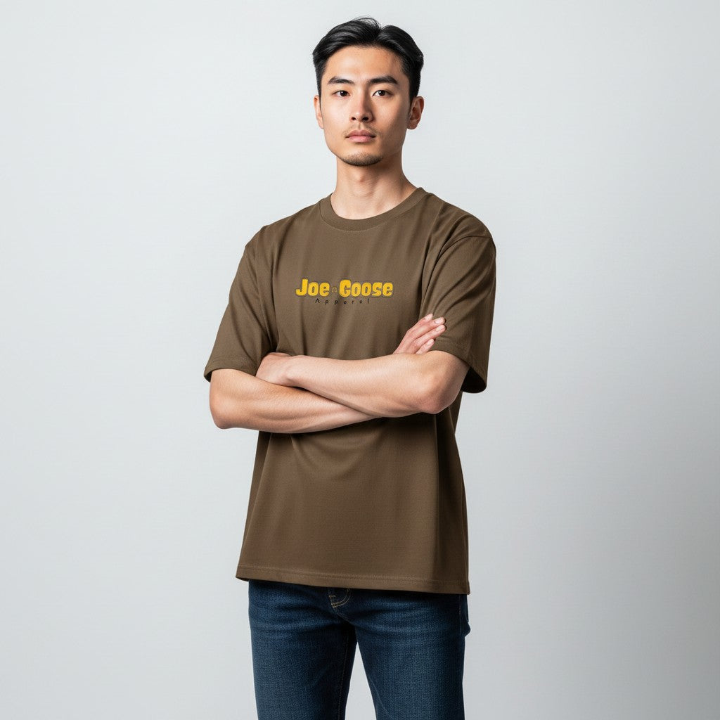 Model wearing a brown Joe the Goose Apparel heavy weight cotton t-shirt with a relaxed fit and yellow logo graphic.