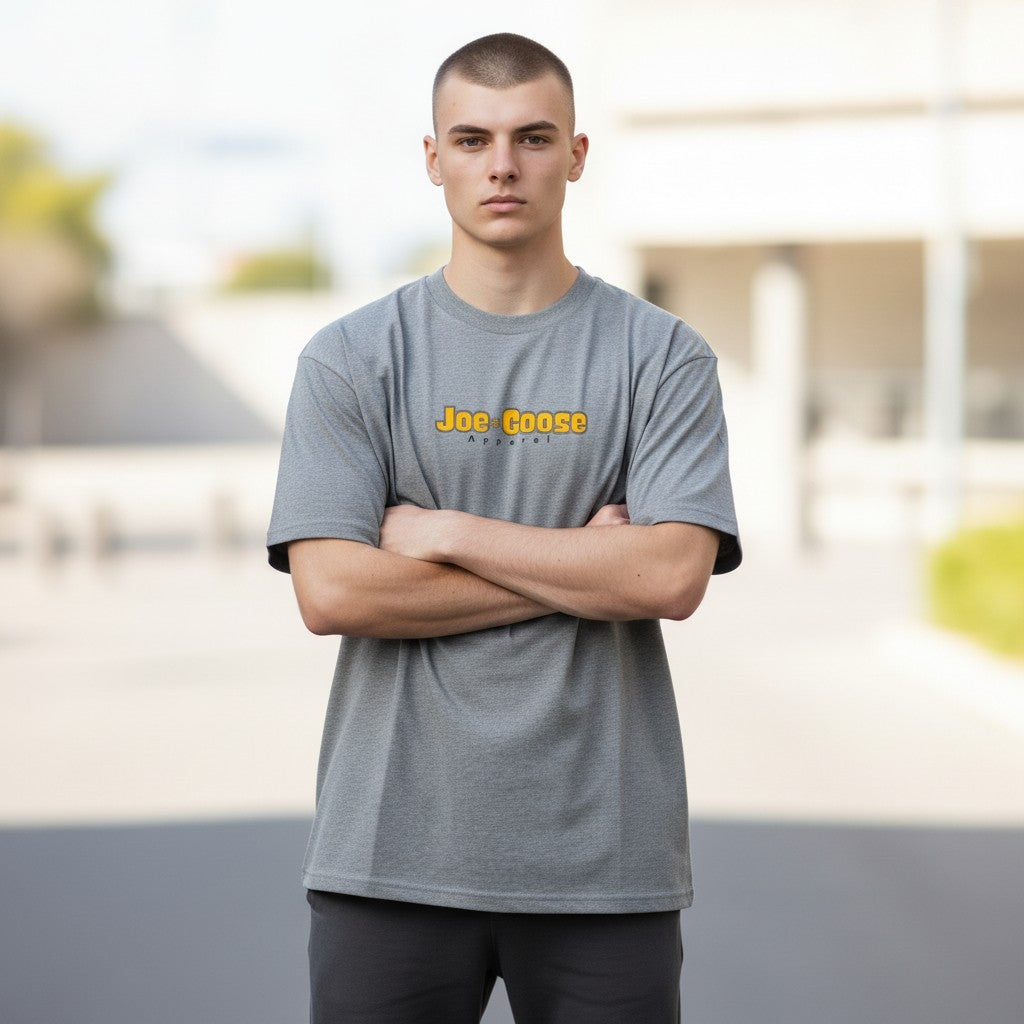 Model wearing a grey Joe the Goose Apparel heavy cotton tee with a relaxed fit and yellow logo on the chest.