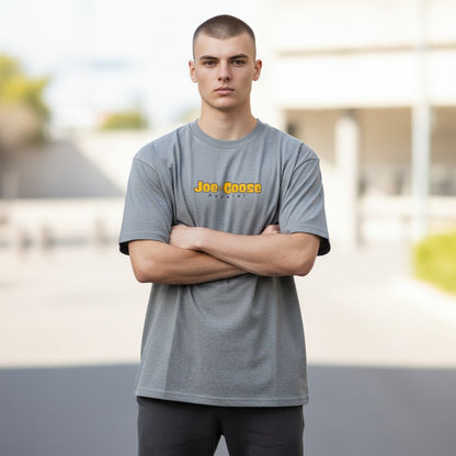 Model wearing a grey Joe the Goose Apparel heavy cotton tee with a relaxed fit and yellow logo on the chest.