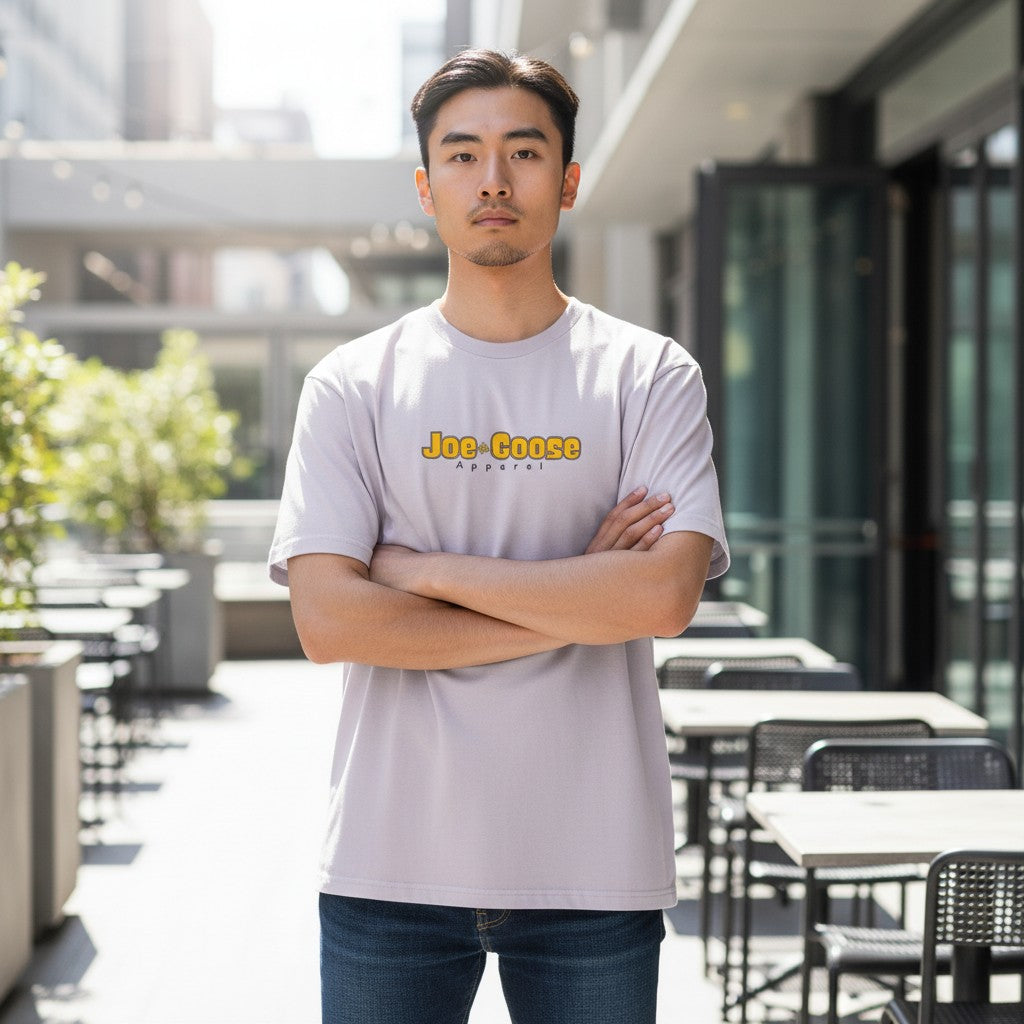 A man wearing a Joe the Goose Apparel heavy weight cotton t-shirt in light grey with a relaxed fit and logo print.