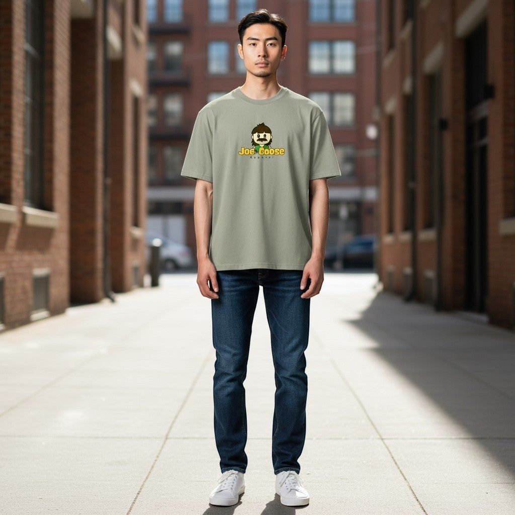 Model wearing a sage green Joe the Goose Apparel heavy cotton t-shirt with a graphic print in an urban alleyway.