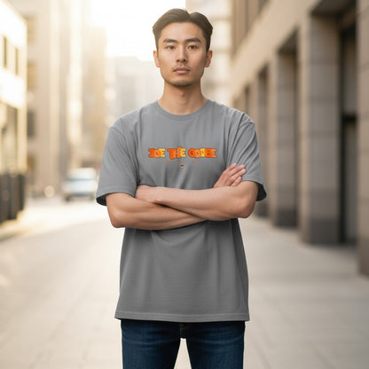 Man wearing a grey Joe the Goose Apparel heavy cotton t-shirt with a stained glass style logo, standing in a city.