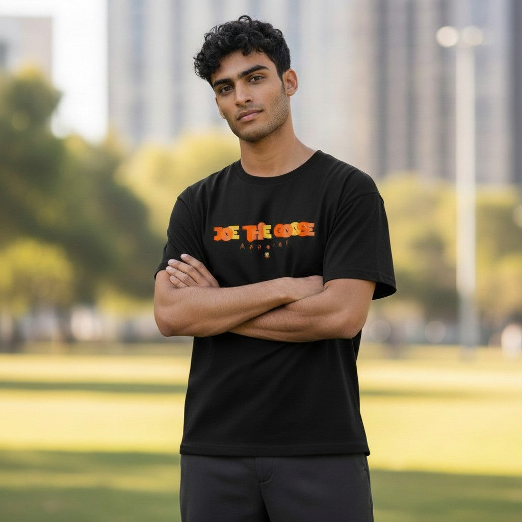 Man wearing a black Joe the Goose Apparel cotton t-shirt with a stained glass style logo outdoors.