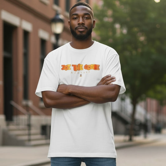 A man wearing a white Joe the Goose Apparel Stained Glass Goose graphic t-shirt with arms crossed outdoors.
